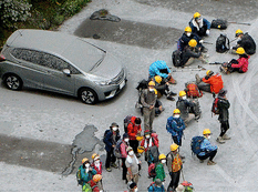 Climbers and a car, covered with volcanic ash, are seen at a parking near Mount Ontake in Kiso town in Nagano prefecture
