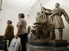 Women walk past a statue in Belorusskaya metro station in Moscow
