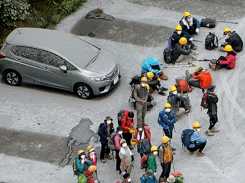 Climbers and a car, covered with volcanic ash, are seen at a parking near Mount Ontake in Kiso town in Nagano prefecture