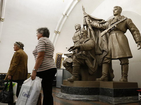 Women walk past a statue in Belorusskaya metro station in Moscow