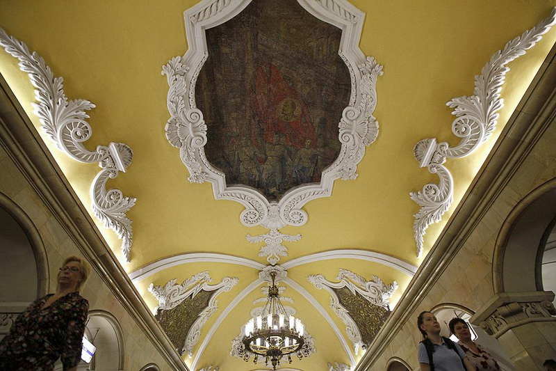 People walk under the mosaic of former Soviet leader Lenin at Komsomolskaya metro station in Moscow