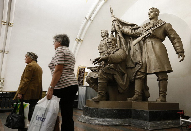 Women walk past a statue in Belorusskaya metro station in Moscow